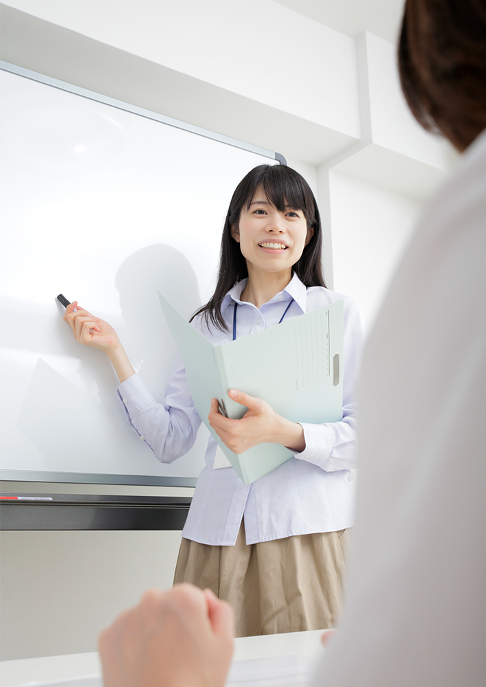 ホワイトボードの前で女性が話している写真